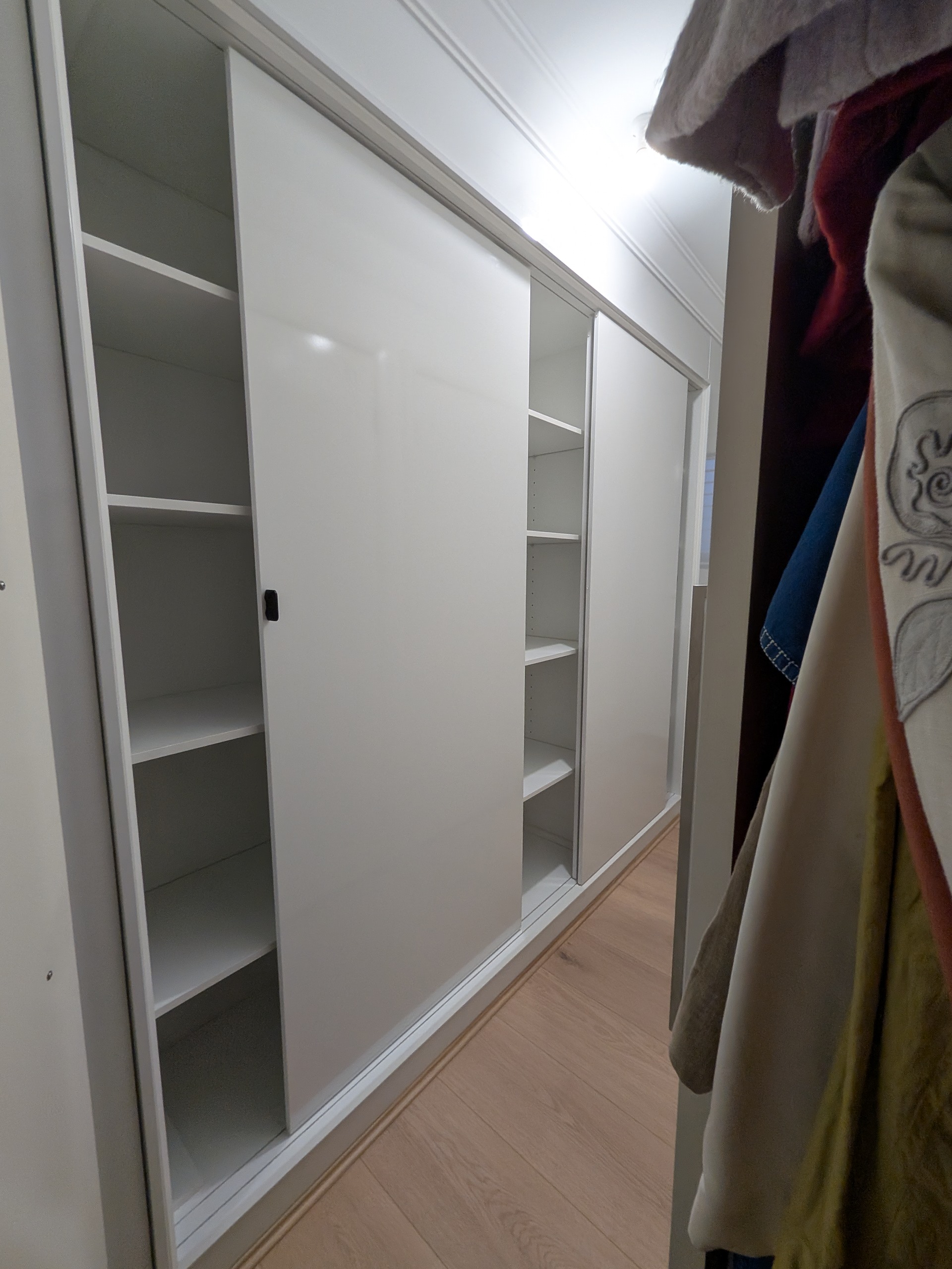 White sliding wardrobe with hidden track system and adjustable shelving by Mojo Craftsman